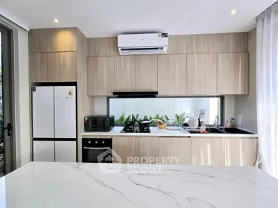 Modern kitchen with sleek cabinetry, marble countertop, and built-in appliances in a bright, airy space.