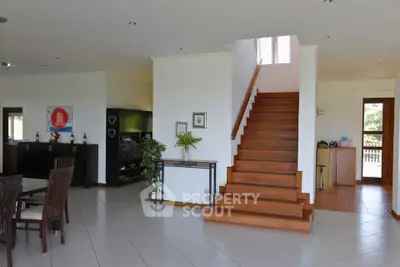 Spacious open-plan living area with elegant staircase and modern dining setup.
