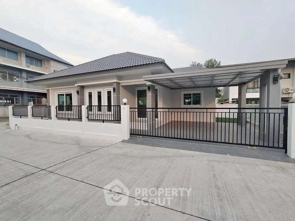 Modern single-story house with gated driveway and contemporary design.
