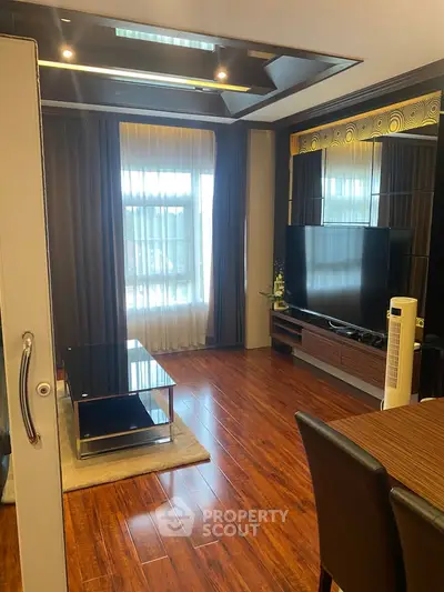 Luxurious living room with hardwood floors, modern decor, and large TV setup.