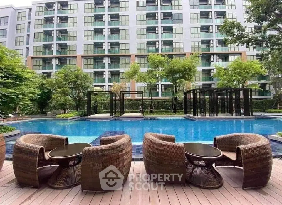 Luxurious apartment complex with stunning pool and modern outdoor seating.