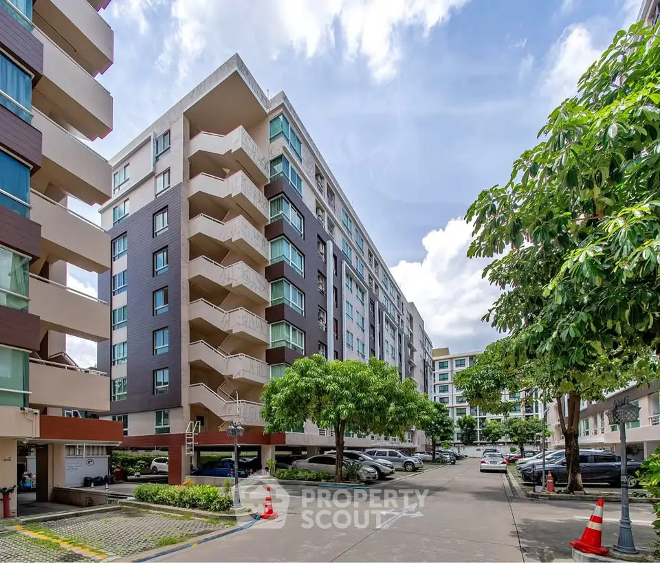 Modern apartment complex with lush greenery and ample parking space