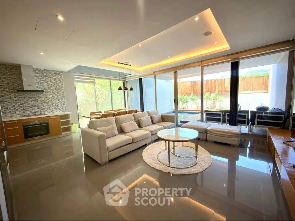 Spacious modern living room with open kitchen and large windows leading to a patio.