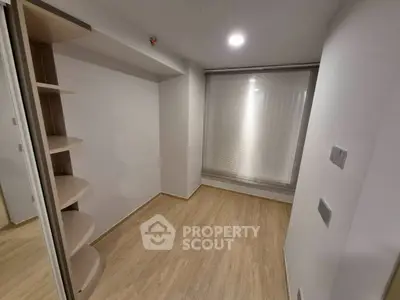 Minimalist small room with wooden flooring and built-in shelves, perfect for storage or study.