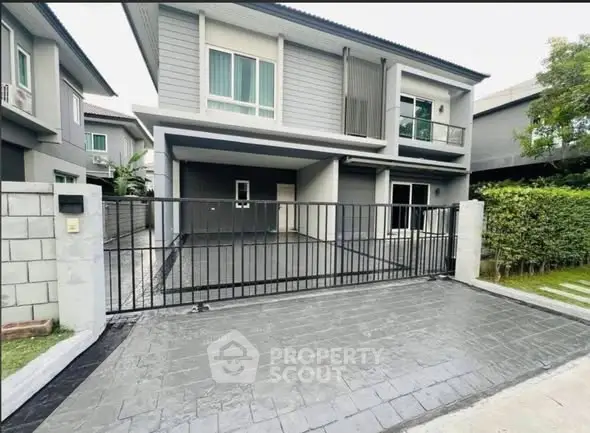 Modern two-story house with gated driveway and contemporary design.
