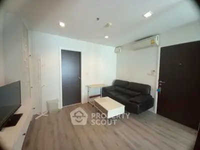 Modern living room with sleek black sofa and wall-mounted TV in a cozy apartment.