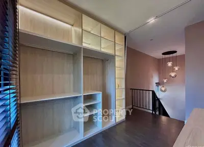 Spacious modern walk-in closet with elegant lighting and wooden finishes.