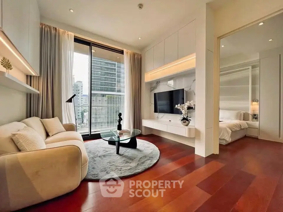 Modern living room with city view, elegant decor, and open layout connecting to bedroom.