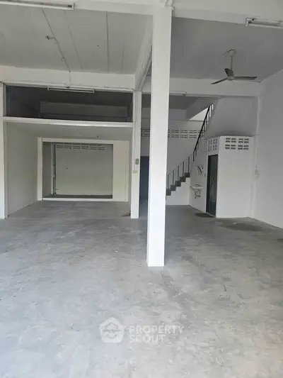 Spacious open-plan interior with high ceilings and modern staircase, ideal for versatile use.