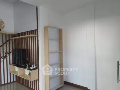 Modern living room with minimalist design and wooden accents, featuring a sleek TV stand and open shelving.