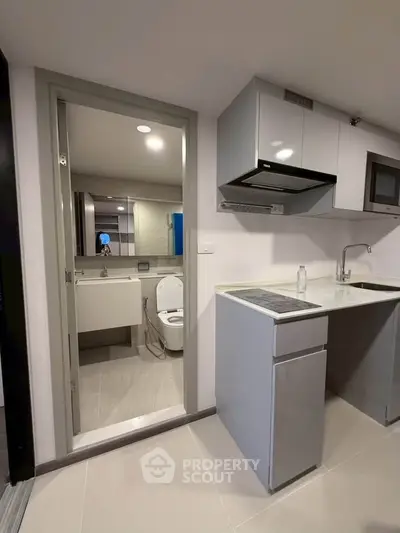 Modern compact kitchen with adjacent bathroom in sleek apartment