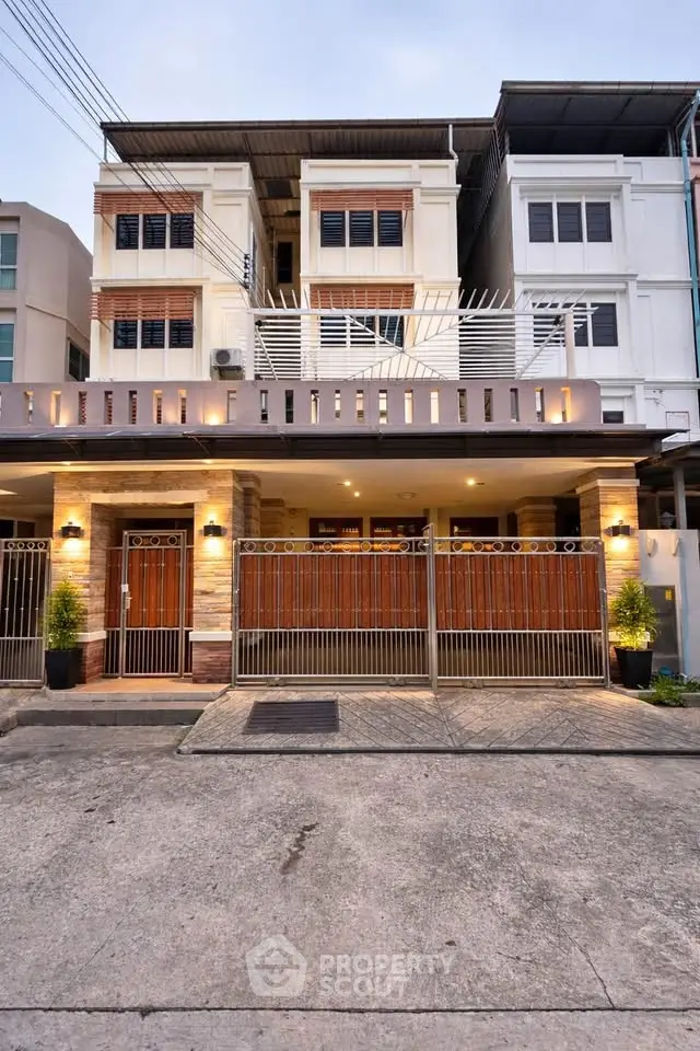 Modern multi-story townhouse with stylish facade and gated entrance in urban setting.