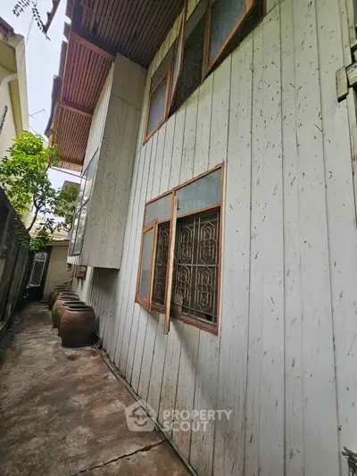 Charming rustic exterior of a wooden house with traditional windows and a narrow pathway, perfect for cozy living.