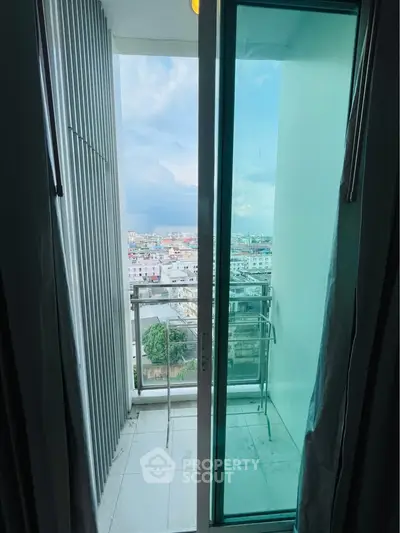 Modern apartment balcony with stunning city view and sleek glass door.