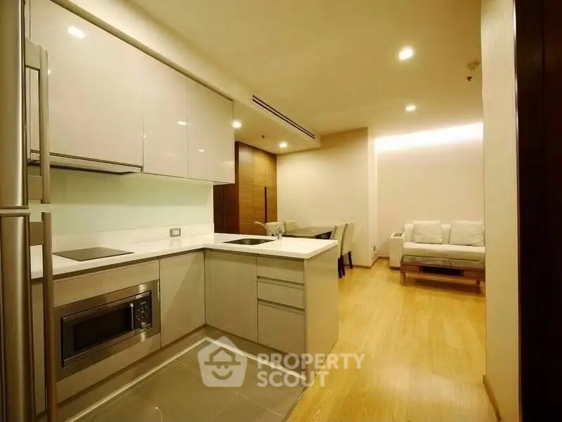 Modern open-layout kitchen with sleek cabinetry and cozy living area in a stylish apartment.