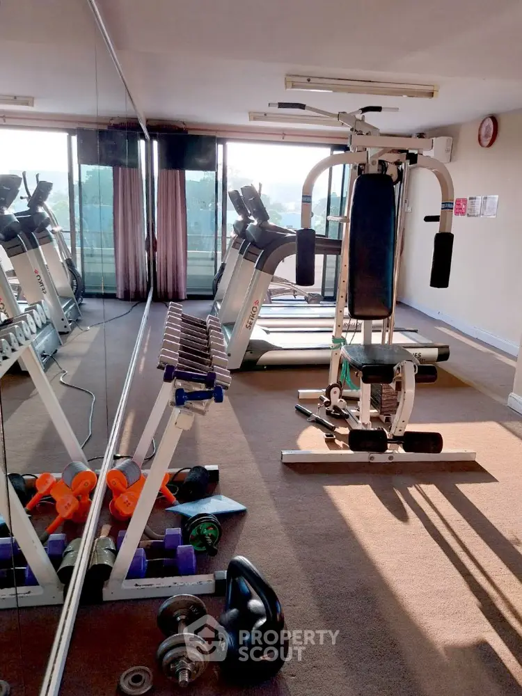 Spacious gym with modern exercise equipment and large mirrors in a residential building.