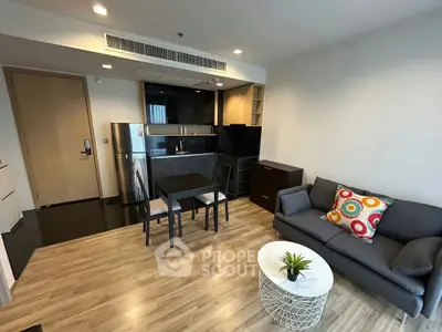 Modern living room with open kitchen, stylish decor, and cozy seating area in a contemporary apartment.