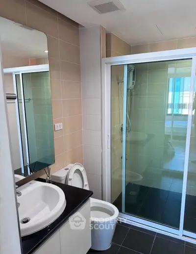 Modern bathroom with glass shower enclosure and sleek fixtures in a contemporary apartment.