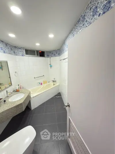 Spacious bathroom with modern fixtures and elegant tile design, featuring a luxurious bathtub and ample counter space.