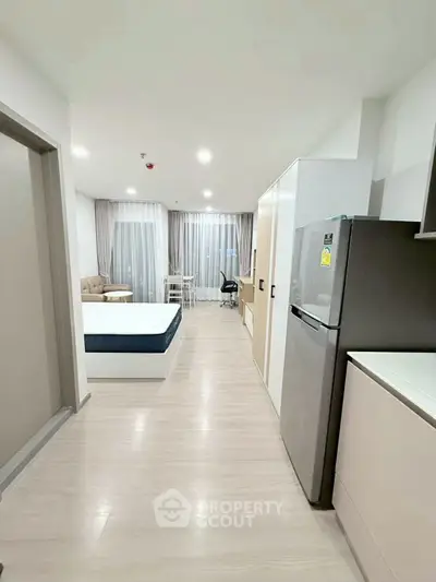 Modern studio apartment with open layout, featuring a cozy living area, bed, and kitchen with sleek appliances.