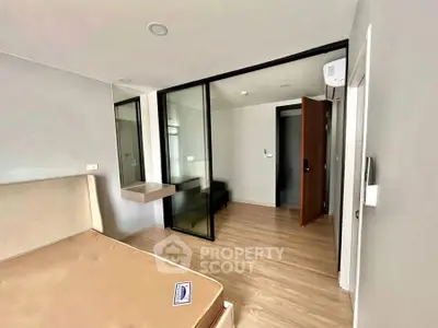 Modern bedroom with glass partition and wooden flooring in a stylish apartment.