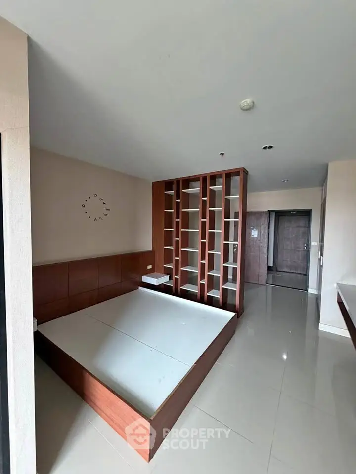 Spacious modern bedroom with built-in wooden shelving and sleek tile flooring