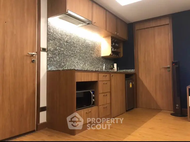 Modern kitchen with wooden cabinets and granite backsplash in cozy apartment.