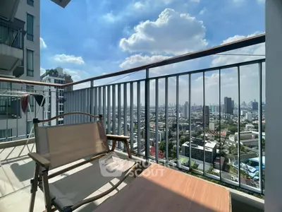 Stunning city view from a high-rise balcony with seating area.