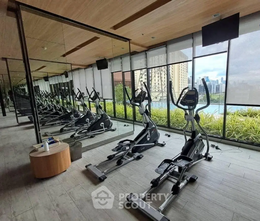 Modern gym with city view and exercise equipment in luxury building.