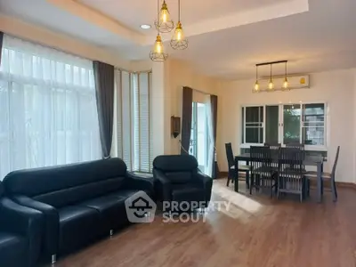 Spacious living room with modern black sofas and elegant dining area