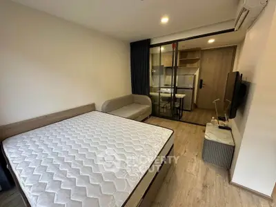 Modern studio apartment with cozy living area and glass partitioned kitchen.