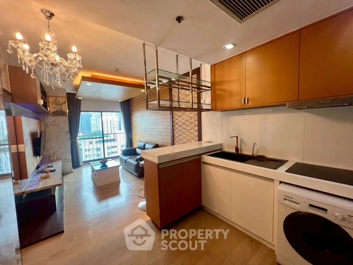 Modern open-layout living room and kitchen with chandelier and city view