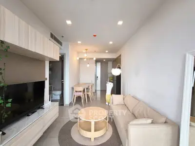 Modern living room with beige sofa, round coffee table, and dining area in open layout apartment.