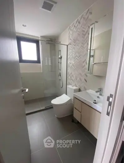 Modern bathroom with sleek design, featuring a glass shower enclosure and contemporary fixtures.