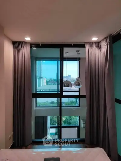 Modern bedroom with floor-to-ceiling windows offering stunning city view