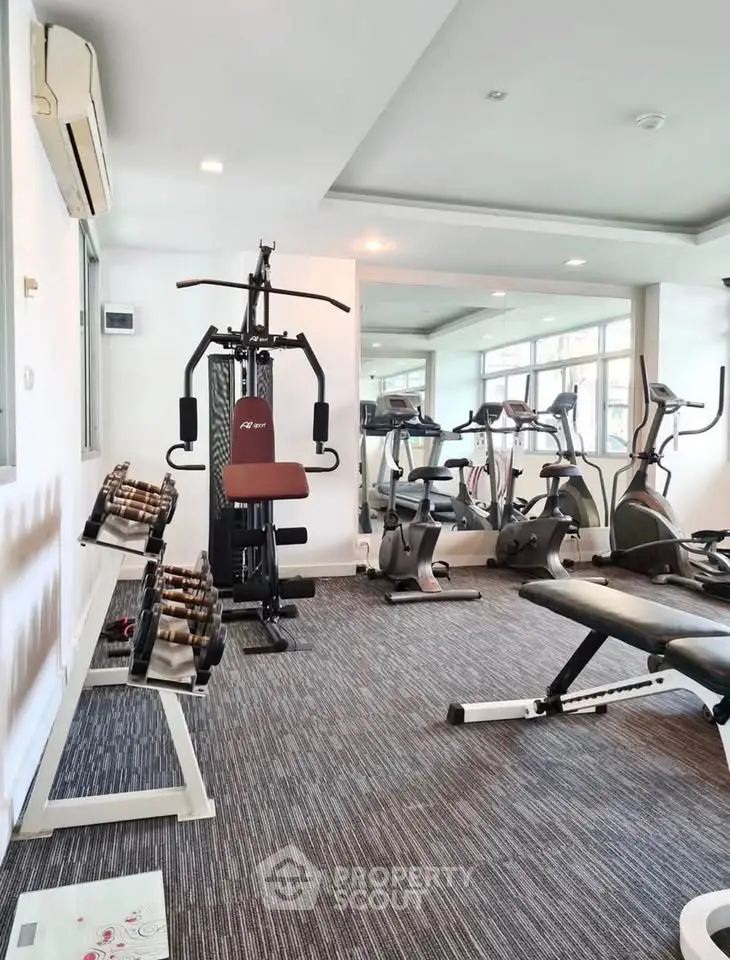 Modern gym with state-of-the-art fitness equipment and large windows for natural light.
