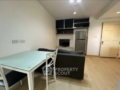 Modern living room with sleek furniture and open layout, featuring a compact kitchen and stylish decor.