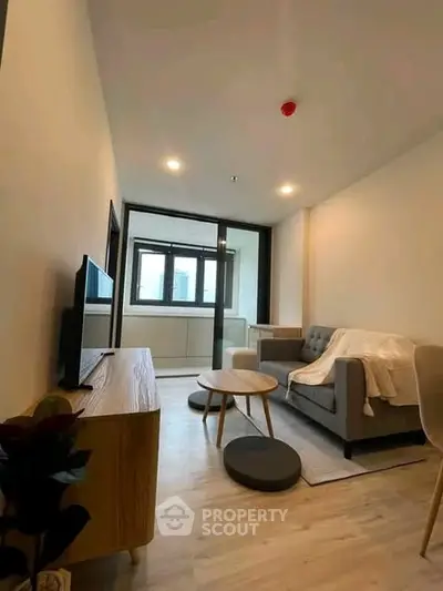 Modern living room with cozy sofa and TV, featuring stylish decor and natural light.