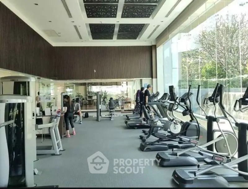 Modern gym with large windows and state-of-the-art exercise equipment in a luxury building.