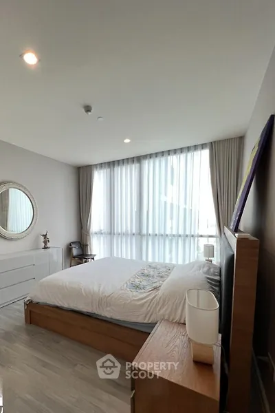 Spacious bedroom with modern decor and large window offering natural light.