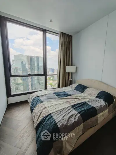 Modern bedroom with large window offering stunning city view in high-rise apartment.