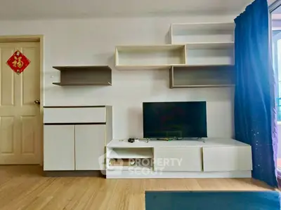Modern living room with stylish shelving and TV unit, featuring sleek design and natural light.