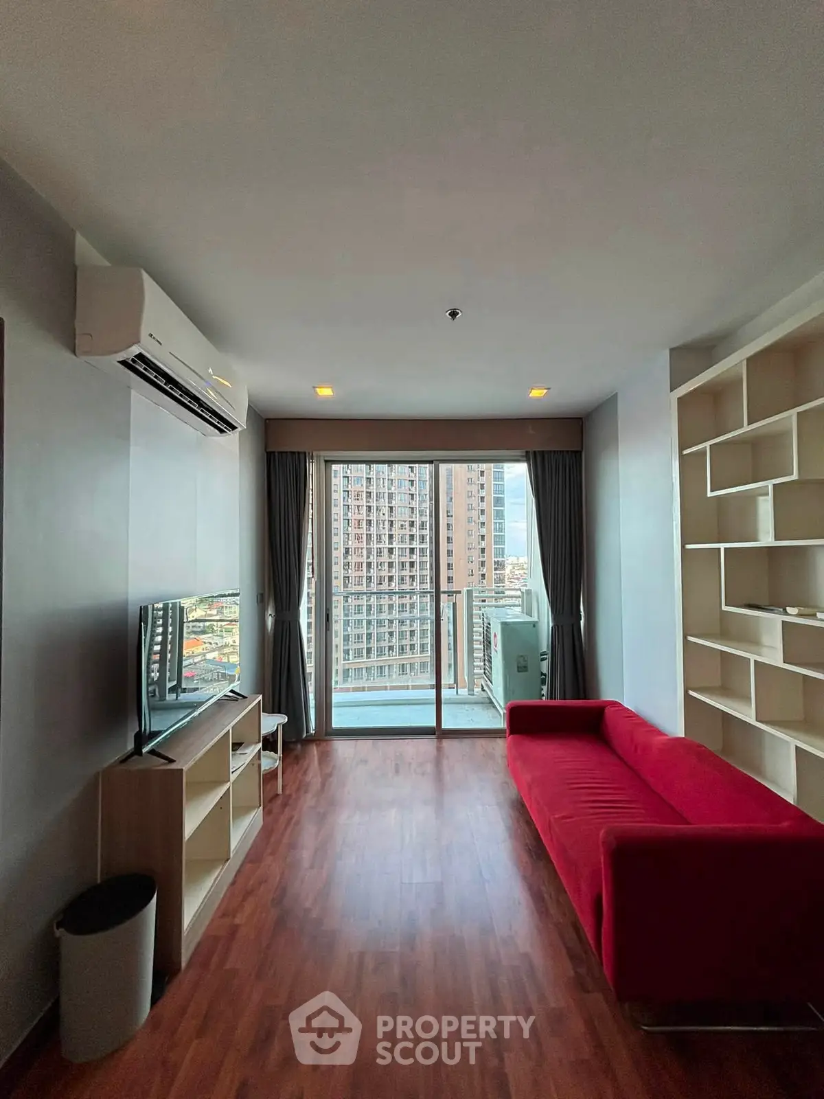 Modern living room with red sofa and city view balcony in high-rise apartment