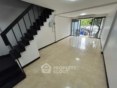 Spacious modern living room with sleek staircase and large windows offering natural light.