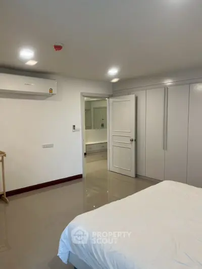 Spacious modern bedroom with sleek white wardrobe and air conditioning.