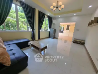 Spacious living room with modern furniture and large windows offering garden views.