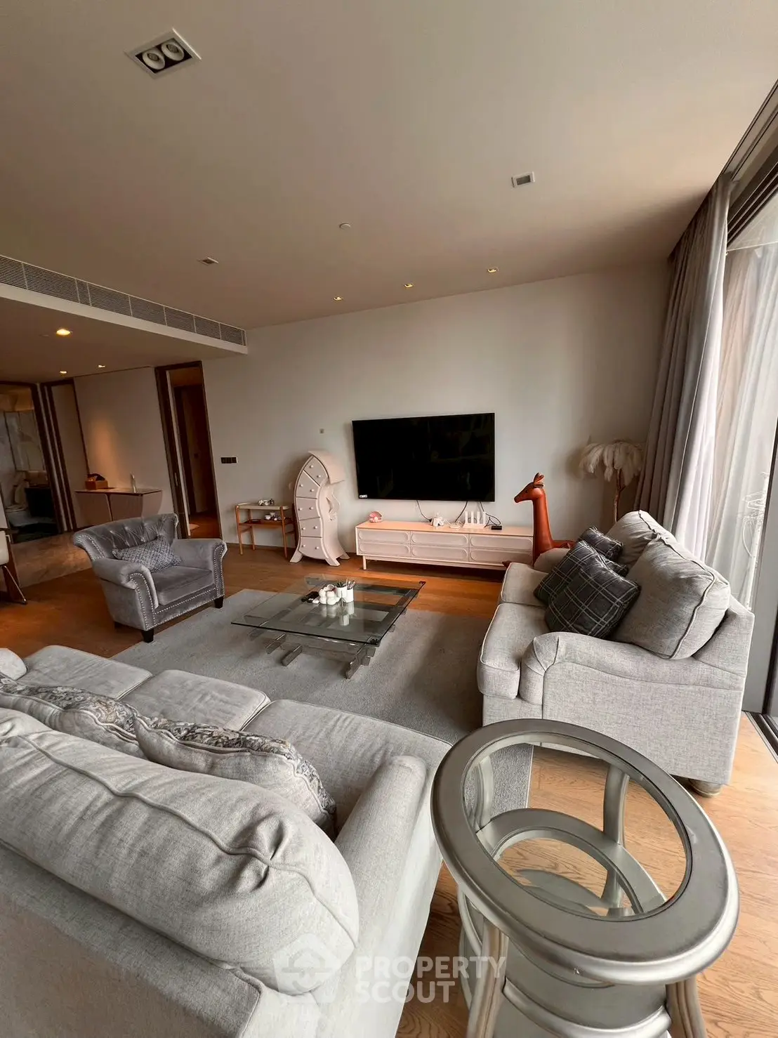 Spacious modern living room with stylish furniture and large TV, perfect for relaxation.