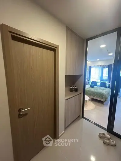 Modern apartment entrance with sleek wooden door and view into stylish bedroom