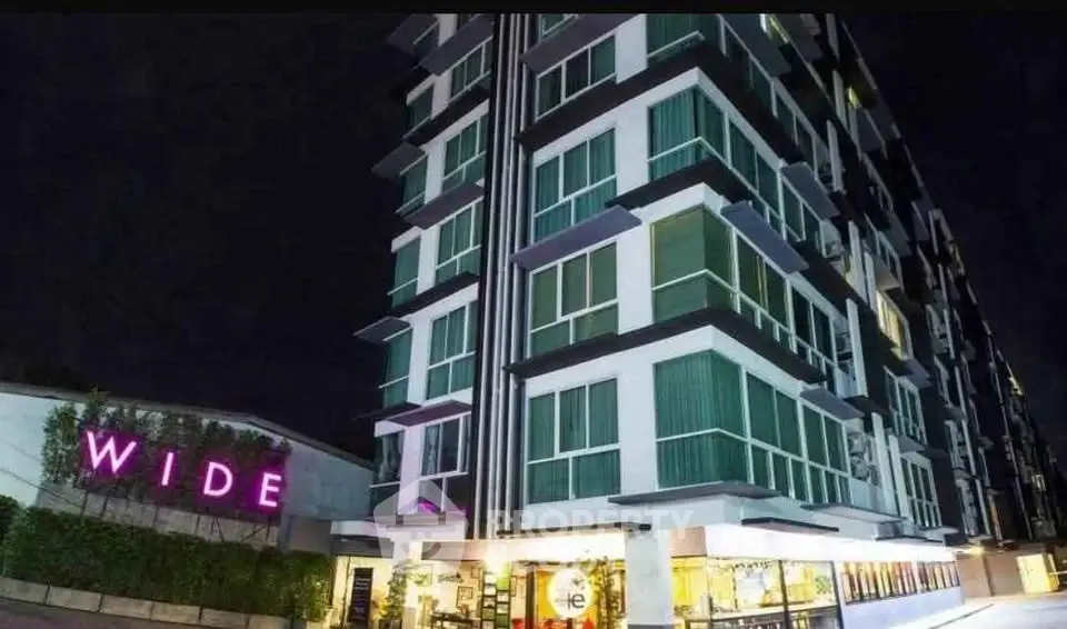 Modern high-rise building exterior with illuminated signage at night