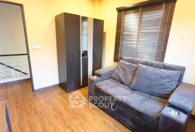 Cozy living room with plush gray sofa and modern wardrobe, featuring warm wooden flooring and stylish blinds.